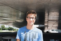portrait de Fabio, lunettes, bâtiment, t-shirt bleu ciel