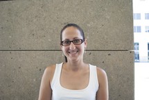 portrait d'Aline, lunettes rouges, mur brun clair, t-shirt blanc