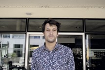 portrait de Basile, cheveux noirs, chemise bleue, vitre, bâtiment, porte