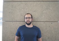 portrait de Yann, lunettes, mur brun clair, t-shirt bleu marin